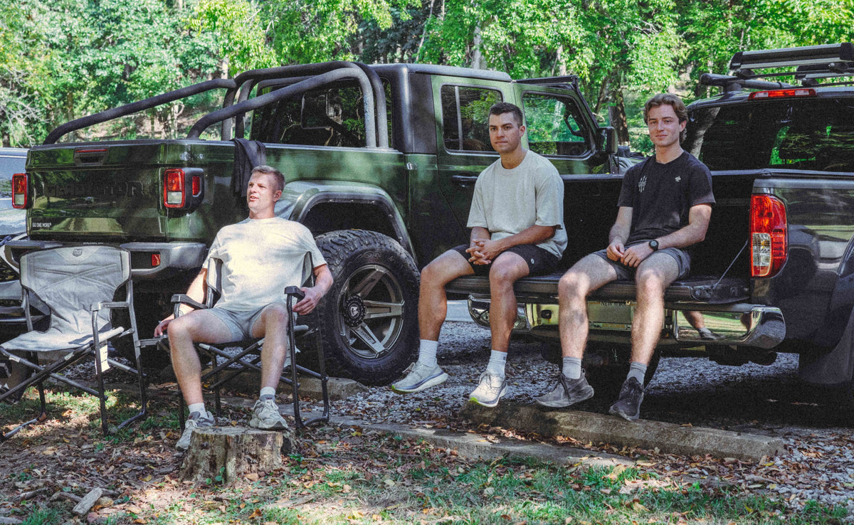 Three runners relaxing together by a truck after a group run